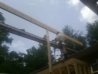 Carpenter setting a ridge beam over a new addition frame — Ice Dam Removal by Roofing Brothers in Docena