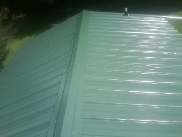 New green metal panels meeting at the ridge of a roof — Flat Roof Repair work by our crew in Docena