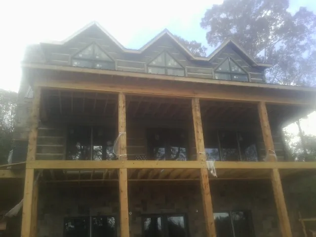 Dormers and porch framing on a large log home under construction — Roof Coating work by our crew in Docena