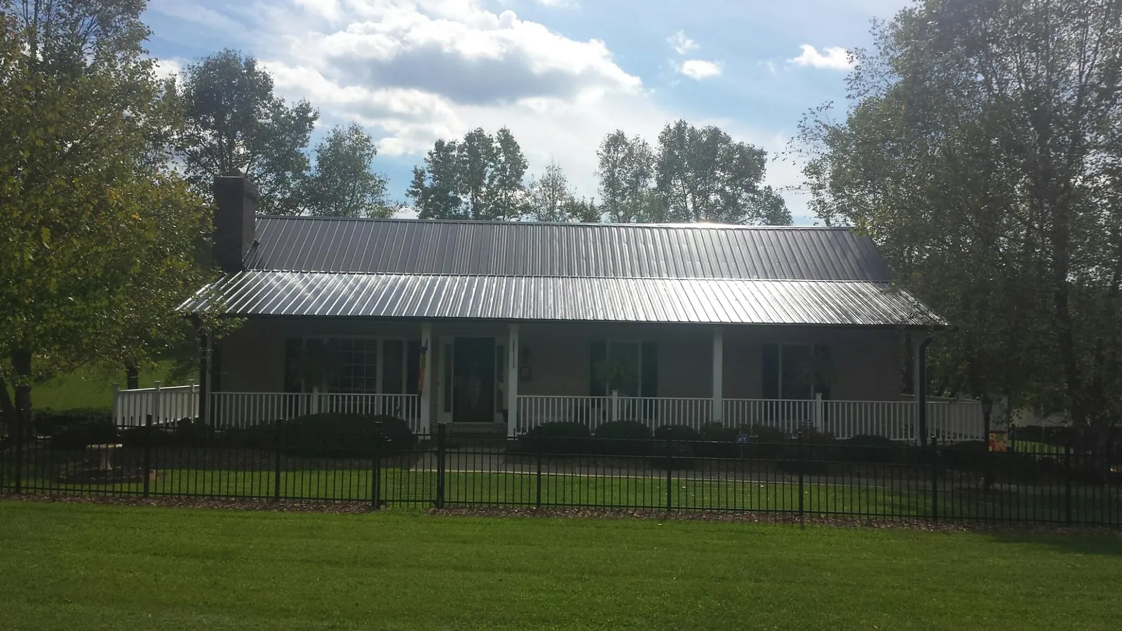 Gray metal roof on a brick ranch with a full width front porch — Gutter Guard Installation work by our crew in Docena